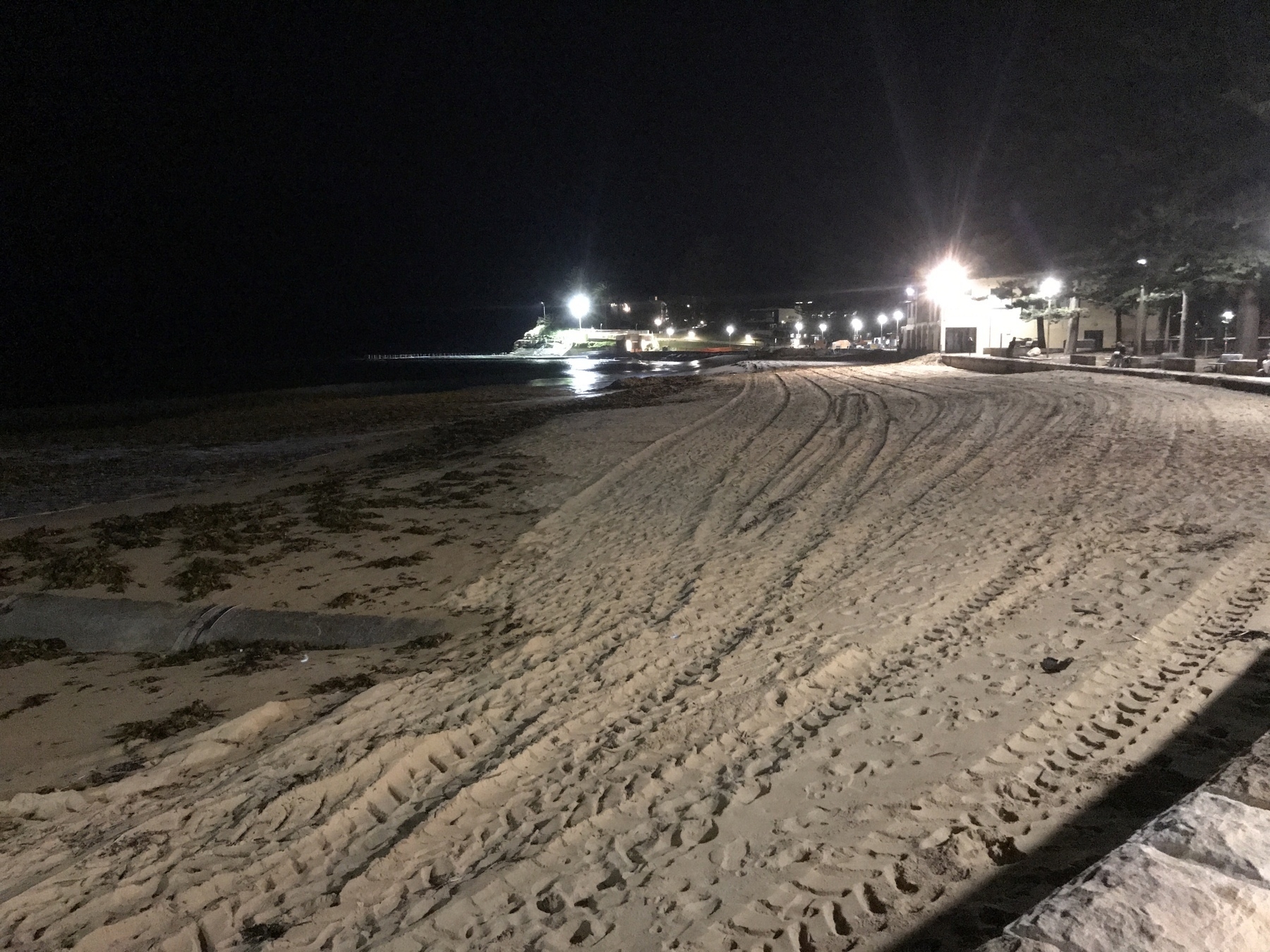 Long stretch if beach at night with lights in the distance
